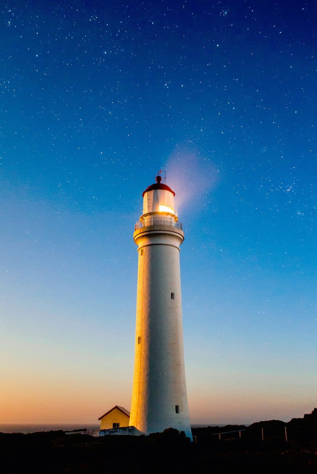 A white lighthouse against a starry twilight sky